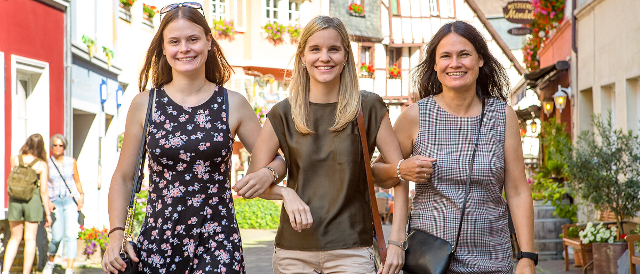 Drei Personen beim Shopping in der Altstadt von Bernkastel-Kues Das Foto zeigt drei Personen, die in der Altstadt von Bernkastel-Kues unterwegs sind. Sie schlendern eingehakt durch die Burgstraße.