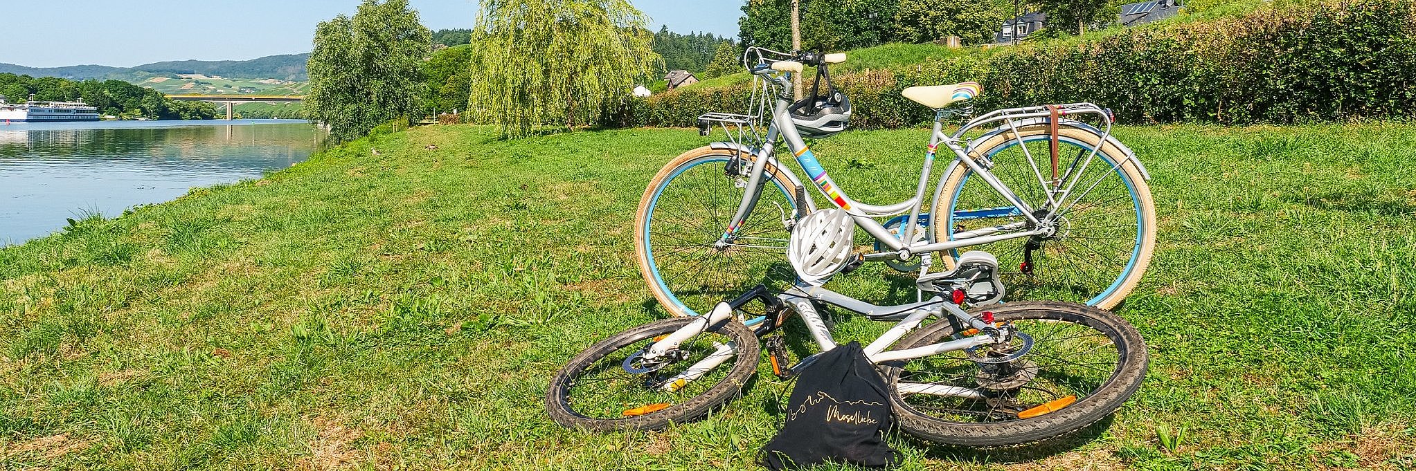 Blick auf zwei Fahrräder, die am Moselufer bei Lieser im grünen Gras Rast abgestellt wurden.
