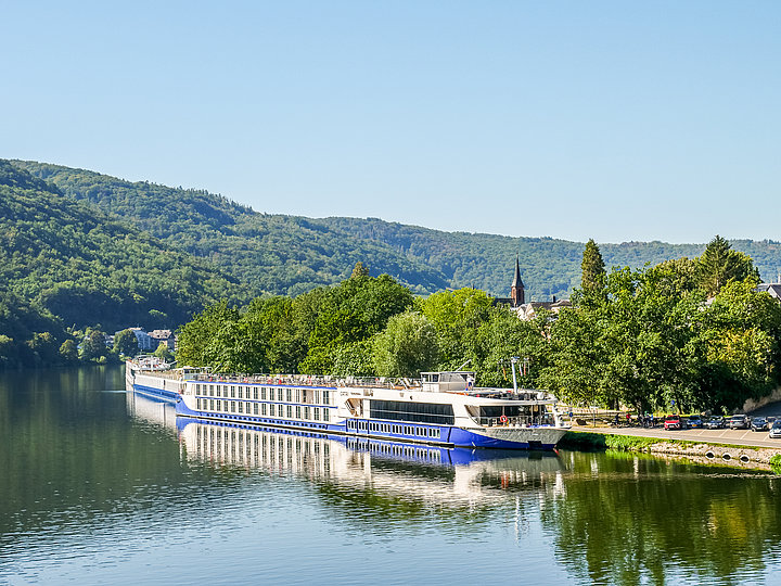 Das Foto zeigt zwei Kreuzfahrtschiffe die jeweils an einem Anleger auf der Mosel bei Bernkastel-Kues angelegt haben.