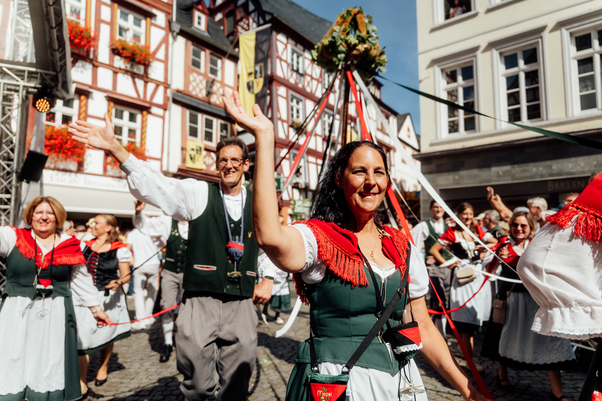 Eine Gruppe von traditionell gekleideten Moselblümchen mit Erntekranz geht beim großen Umzug anlässlich des Weinfestes der Mittelmosel in Bernkastel-Kues mit.